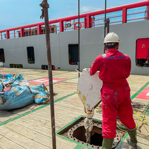 Maritime worker in red coveralls operating equipment on a ship deck symbolizing maritime injury claim